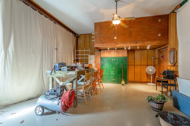 interior space featuring ceiling fan and wooden walls