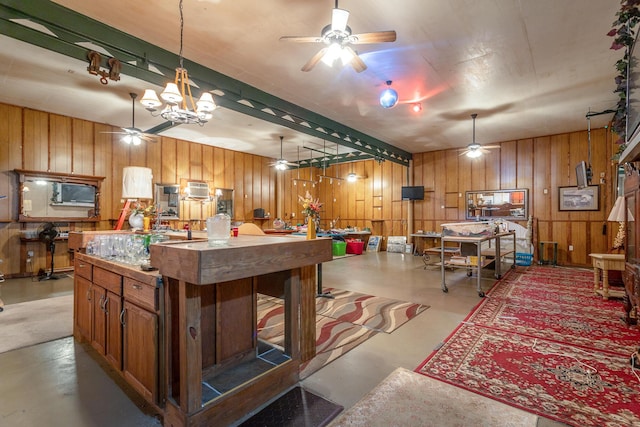 kitchen featuring concrete floors, ceiling fan with notable chandelier, and decorative light fixtures