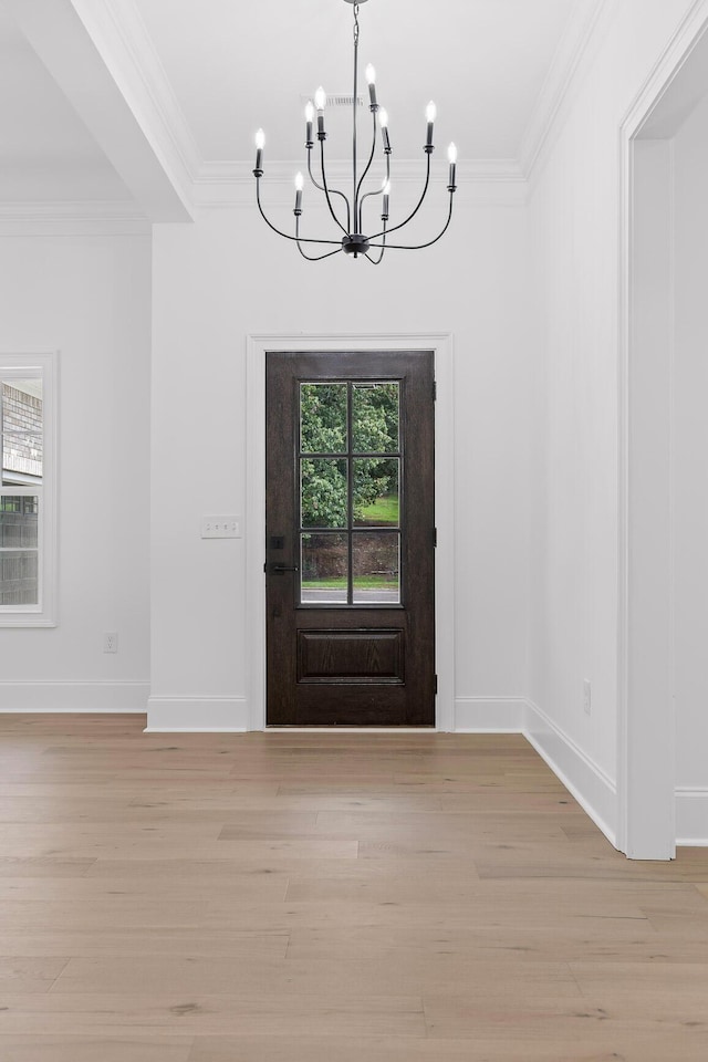 entrance foyer featuring a notable chandelier, ornamental molding, and light hardwood / wood-style flooring