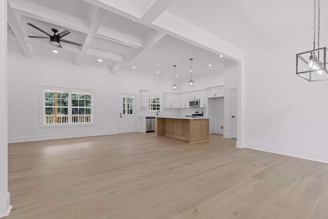 unfurnished living room with beam ceiling, ceiling fan, coffered ceiling, a towering ceiling, and light wood-type flooring