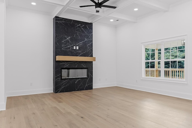 unfurnished living room featuring beam ceiling, ceiling fan, coffered ceiling, light hardwood / wood-style floors, and a fireplace