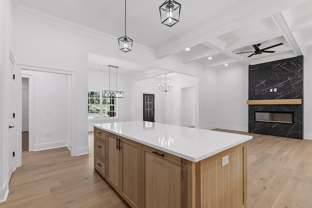 kitchen featuring beam ceiling, coffered ceiling, a high end fireplace, pendant lighting, and a kitchen island