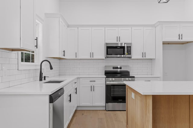 kitchen featuring sink, white cabinets, stainless steel appliances, and light hardwood / wood-style flooring