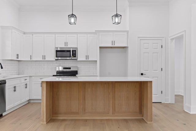 kitchen featuring range, a center island, white cabinetry, and hanging light fixtures