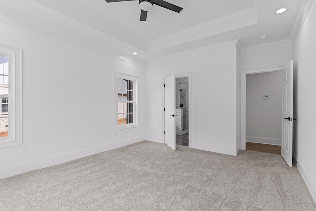 unfurnished bedroom featuring a tray ceiling, multiple windows, ceiling fan, and light colored carpet