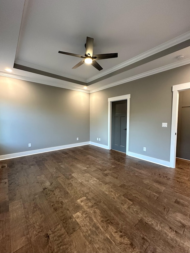 empty room with ceiling fan, dark hardwood / wood-style flooring, crown molding, and a tray ceiling