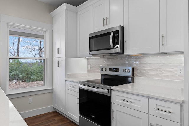 kitchen featuring stainless steel appliances, light stone counters, dark hardwood / wood-style flooring, backsplash, and white cabinets