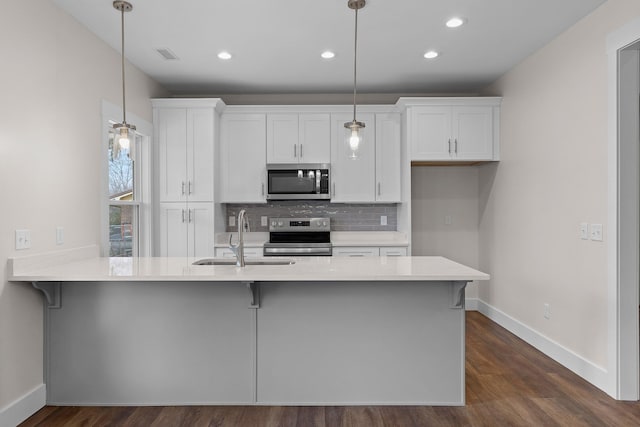 kitchen with pendant lighting, sink, white cabinets, and stainless steel appliances