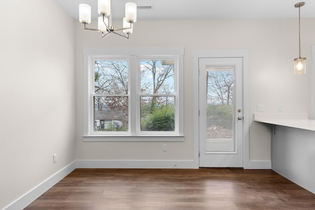 entryway featuring dark wood-type flooring, an inviting chandelier, and a healthy amount of sunlight