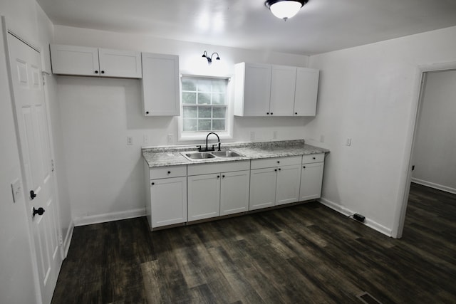 kitchen featuring dark hardwood / wood-style floors, light stone counters, white cabinetry, and sink