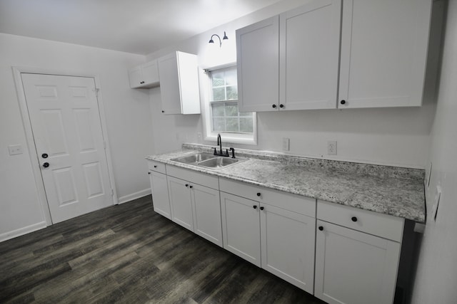 kitchen with white cabinets, dark hardwood / wood-style floors, light stone countertops, and sink