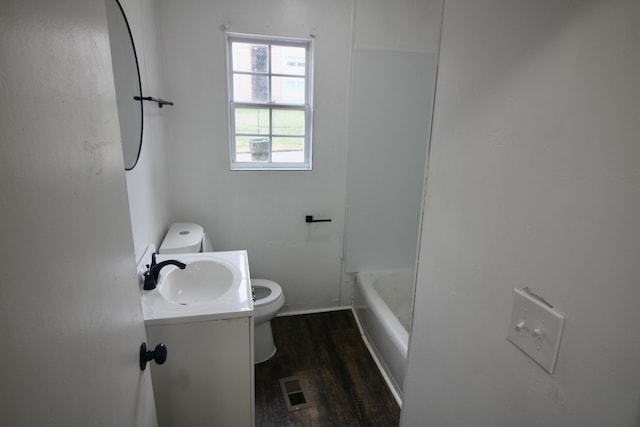 bathroom with a washtub, vanity, hardwood / wood-style flooring, and toilet