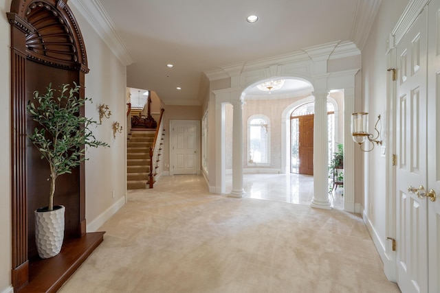 carpeted entryway with ornate columns and crown molding