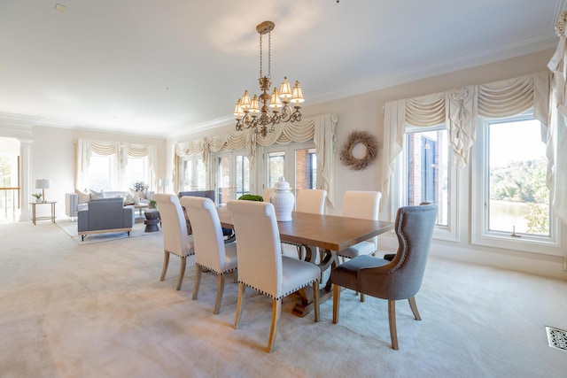 carpeted dining room featuring an inviting chandelier and ornamental molding