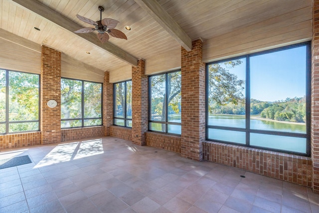 unfurnished sunroom with a wealth of natural light, vaulted ceiling with beams, a water view, and ceiling fan