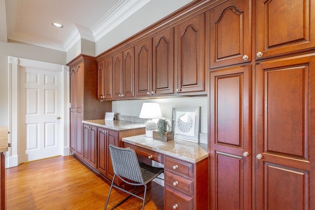 office area featuring built in desk, crown molding, and light hardwood / wood-style flooring