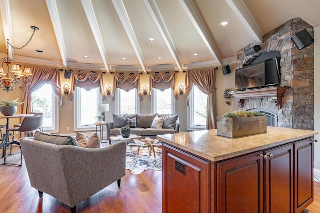 kitchen with light hardwood / wood-style flooring, beam ceiling, a fireplace, and an inviting chandelier