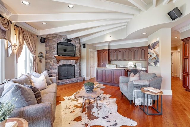 living room featuring a stone fireplace, hardwood / wood-style floors, beamed ceiling, and ornamental molding