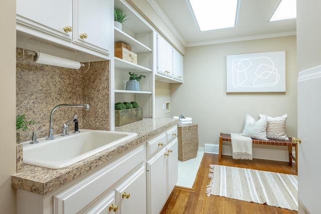 interior space featuring cabinets, ornamental molding, sink, and hookup for a washing machine