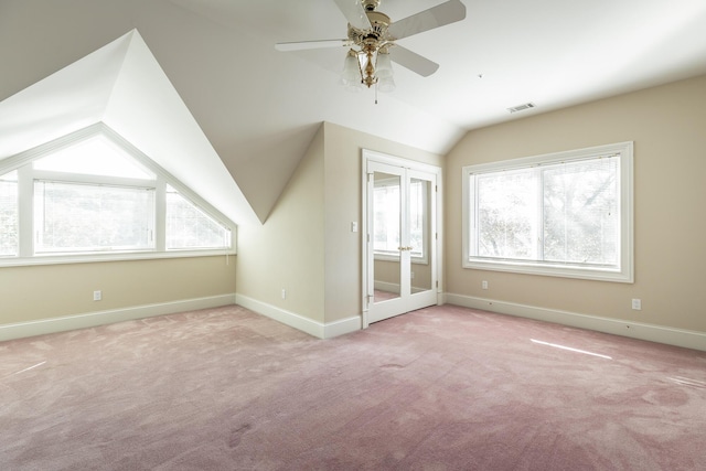 additional living space featuring light carpet, french doors, a wealth of natural light, and lofted ceiling