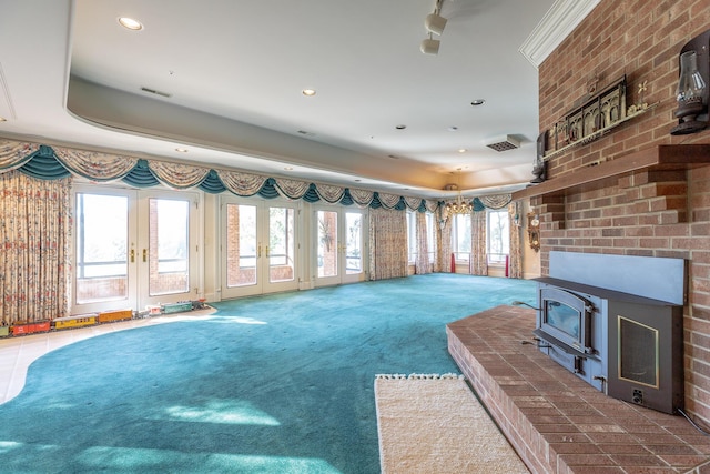 unfurnished living room with carpet, a wood stove, brick wall, and french doors