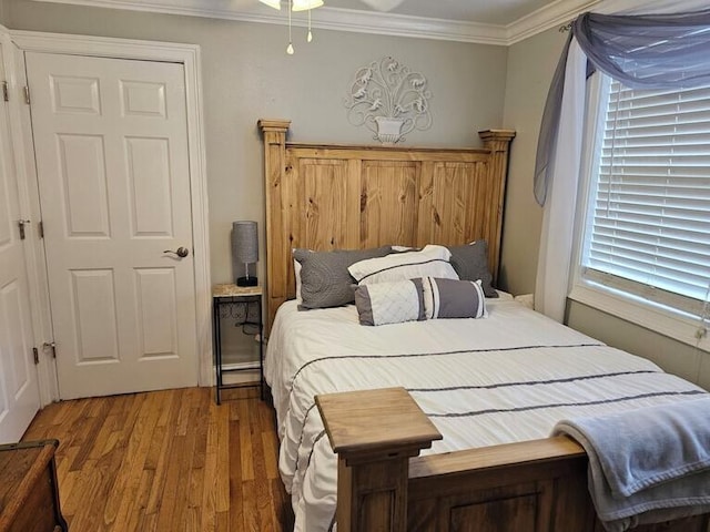 bedroom featuring wood-type flooring, multiple windows, and ornamental molding