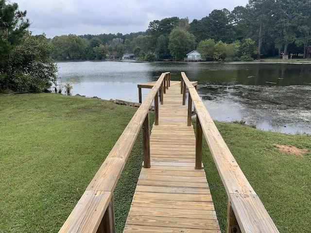 view of dock with a lawn and a water view