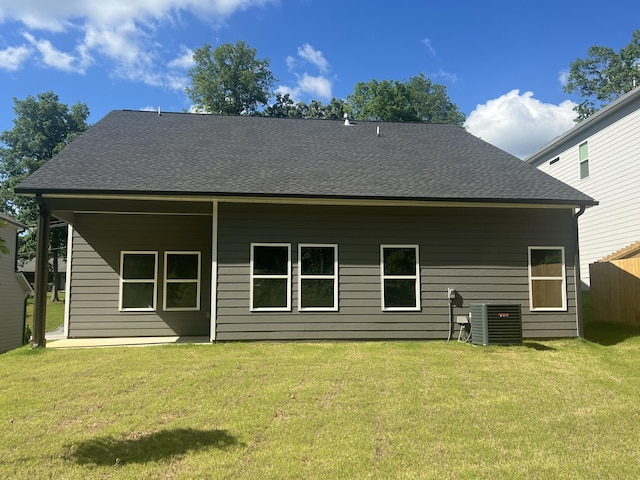 rear view of house featuring central air condition unit and a lawn