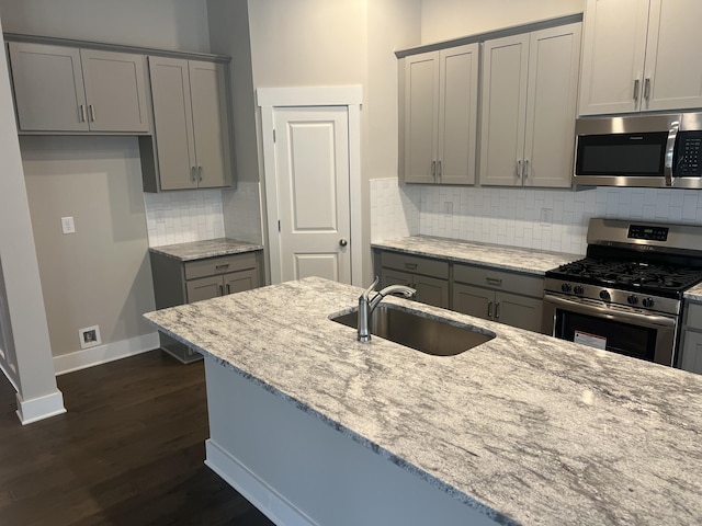 kitchen featuring light stone countertops, sink, appliances with stainless steel finishes, and dark wood-type flooring