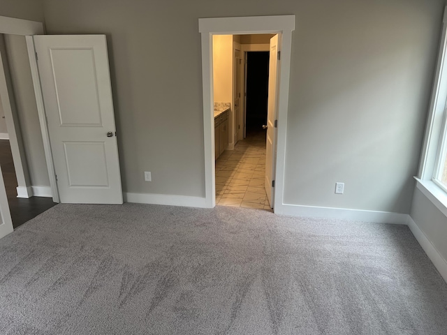 unfurnished bedroom with light carpet and connected bathroom