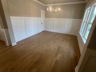 unfurnished dining area featuring wood-type flooring and an inviting chandelier