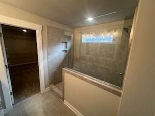 bathroom with a tile shower and tile patterned flooring