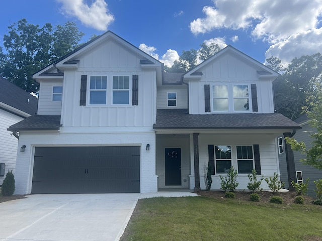 view of front facade featuring covered porch, a front yard, and a garage