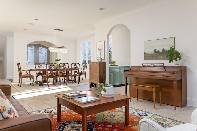 living area featuring light tile patterned floors, baseboards, arched walkways, and ornamental molding