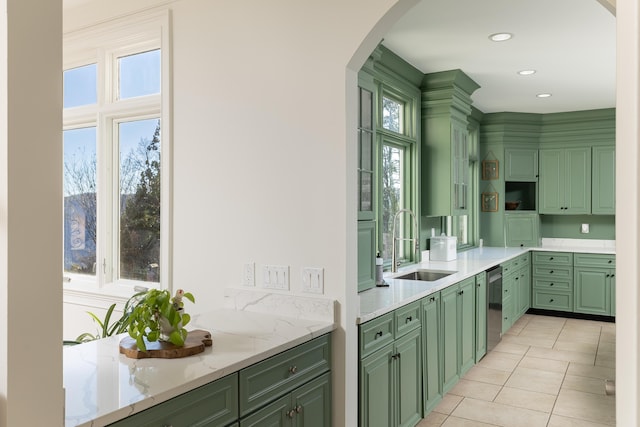 kitchen featuring a sink, arched walkways, stainless steel dishwasher, and green cabinets