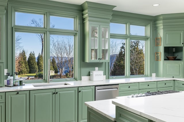 kitchen featuring light stone counters, glass insert cabinets, appliances with stainless steel finishes, and green cabinetry