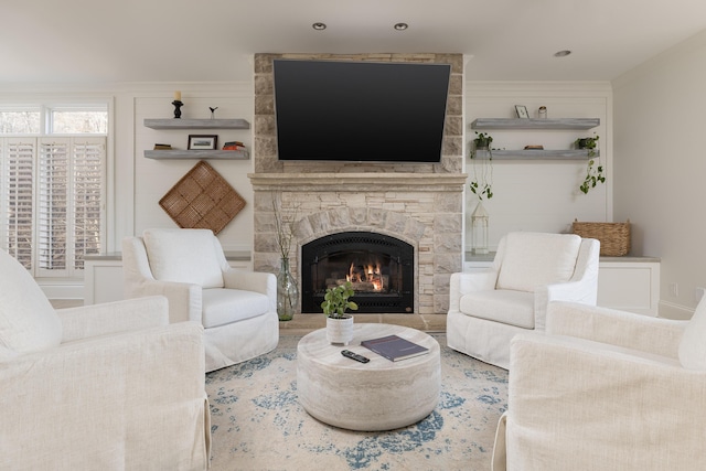 living area featuring a stone fireplace and crown molding