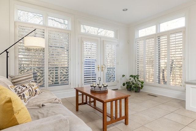 living area featuring light tile patterned flooring, visible vents, and ornamental molding