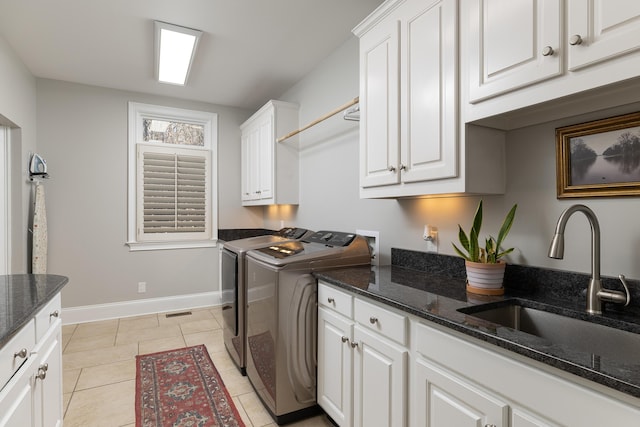 laundry area featuring light tile patterned floors, baseboards, cabinet space, a sink, and independent washer and dryer