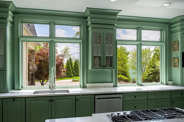 kitchen with appliances with stainless steel finishes, green cabinetry, light stone countertops, and a sink