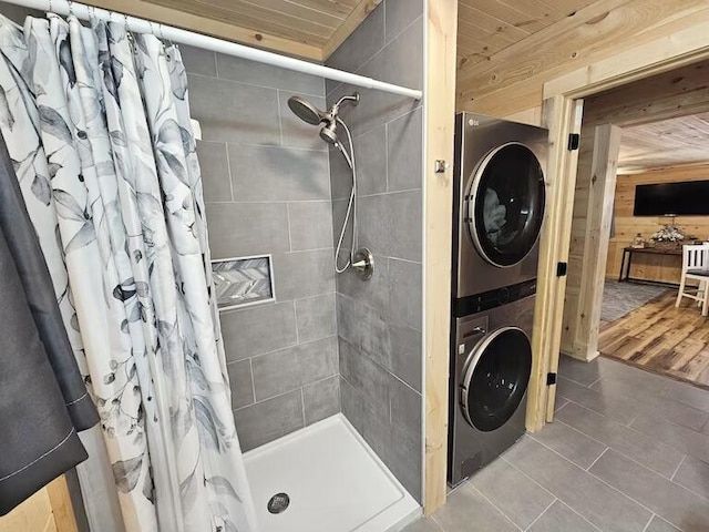 bathroom featuring stacked washer and dryer, tile patterned floors, curtained shower, and wooden walls