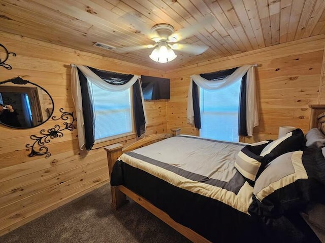 carpeted bedroom featuring ceiling fan, wood ceiling, and wooden walls