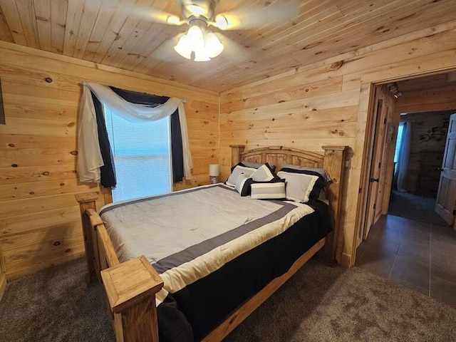 bedroom featuring ceiling fan, wood walls, wooden ceiling, and dark carpet