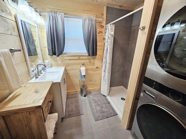 bathroom featuring tile patterned flooring, stacked washing maching and dryer, walk in shower, and wooden walls