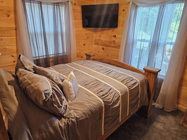 bedroom with carpet, multiple windows, and wooden walls