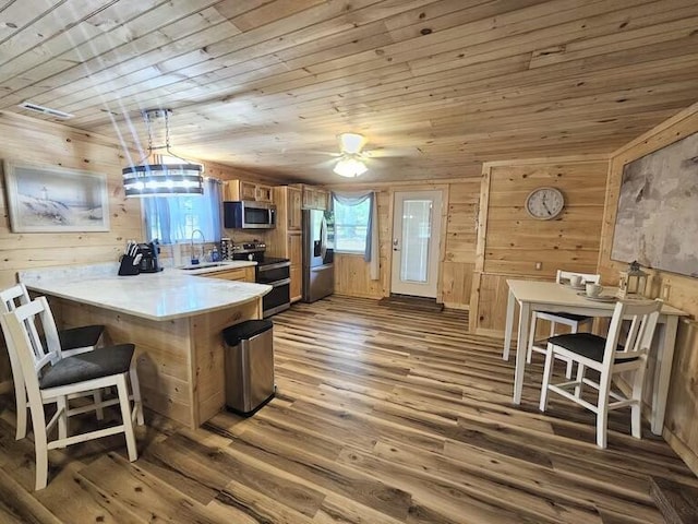 kitchen with kitchen peninsula, stainless steel appliances, hardwood / wood-style flooring, wooden ceiling, and hanging light fixtures