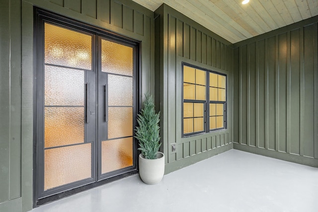 entryway with wooden walls, concrete floors, and wooden ceiling