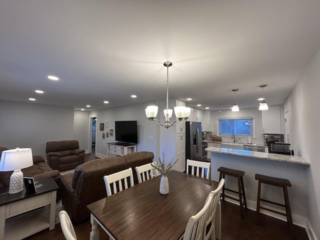 dining space with sink, dark wood-type flooring, and a notable chandelier