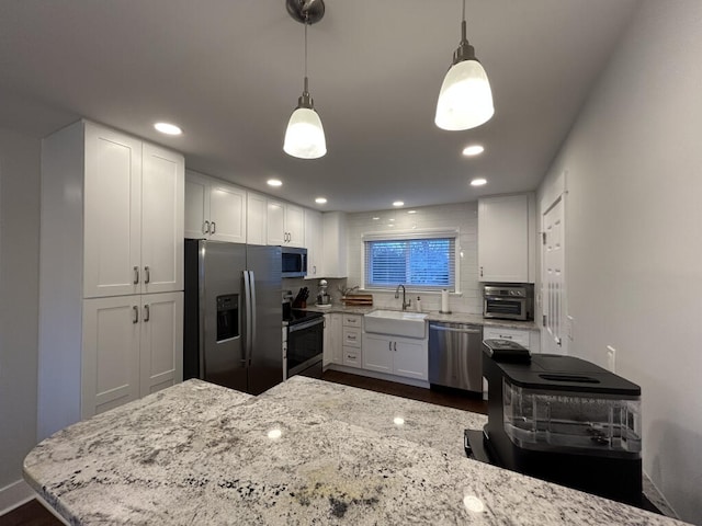 kitchen featuring white cabinetry, sink, hanging light fixtures, backsplash, and appliances with stainless steel finishes