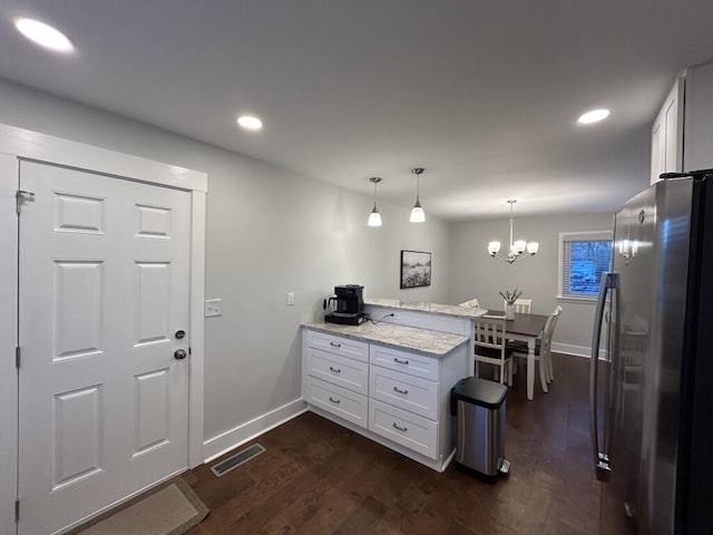 kitchen with stainless steel refrigerator, light stone countertops, white cabinets, and pendant lighting